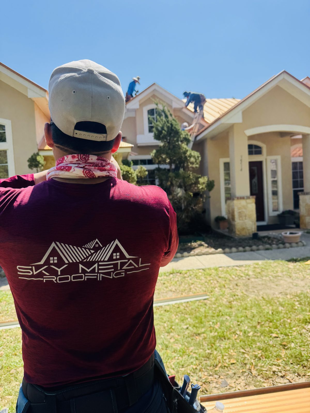 A Sky Metal Roofing technician in a branded shirt working on a roof